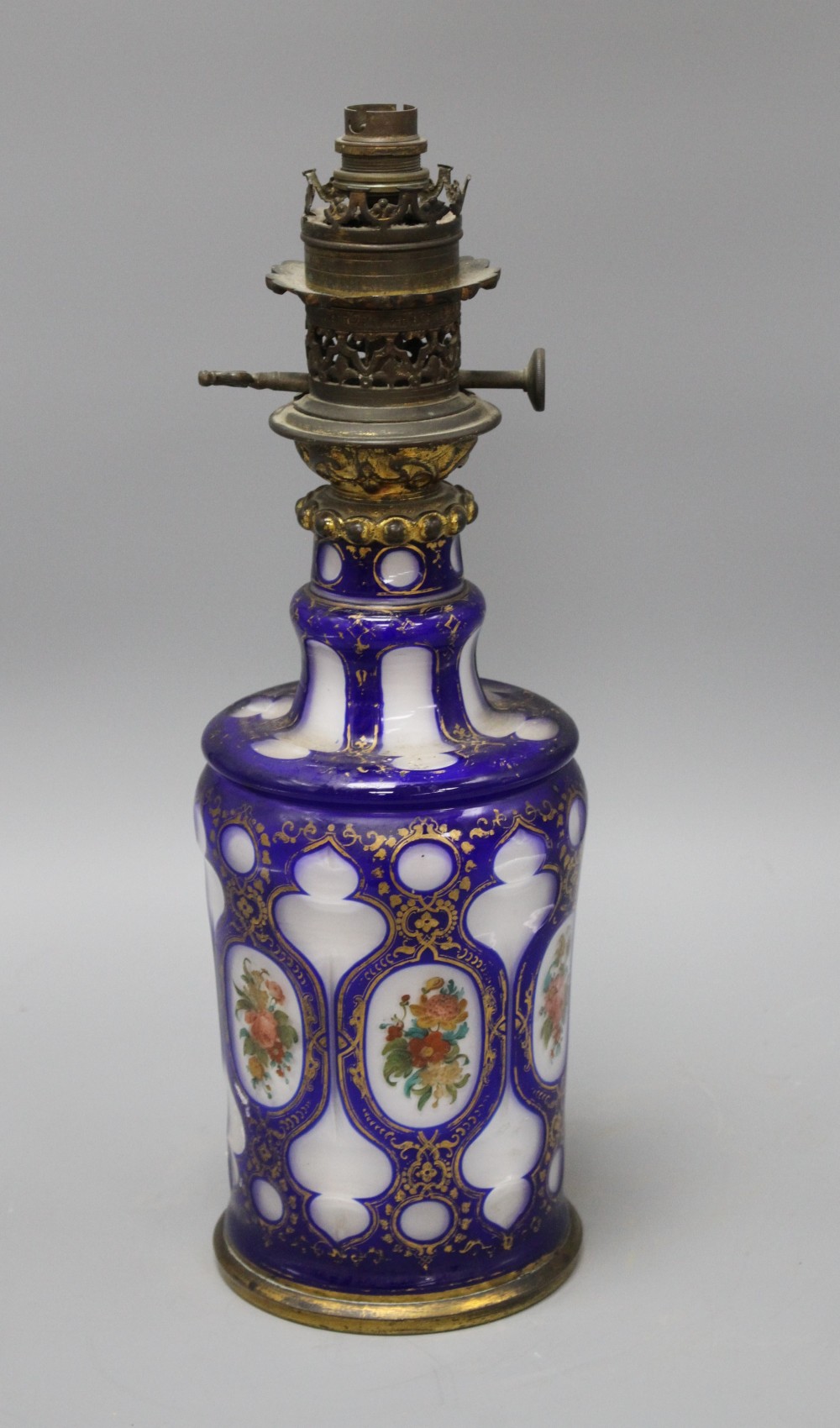 A Bohemian blue overlaid glass oil lamp base, painted with flowers, overall height 42.5cm